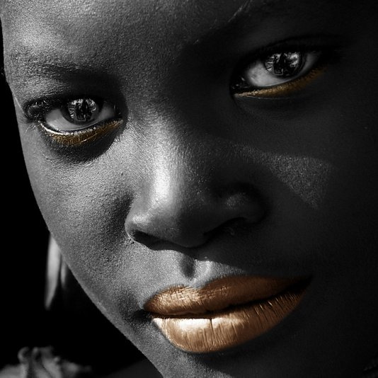 Imagem em preto e branco com alta definição e nitidez. Cores em destaque nos olhos e lábios.