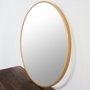Foto lateral, espelho redondo com moldura dourada.